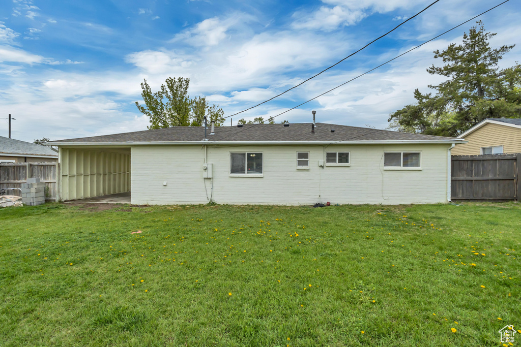 Rear view of property featuring brick siding, a yard, and fence