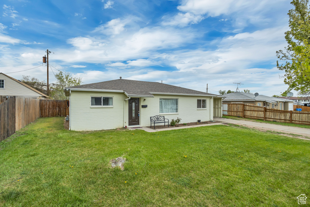 Back of house featuring roof with shingles, a fenced backyard, and a lawn