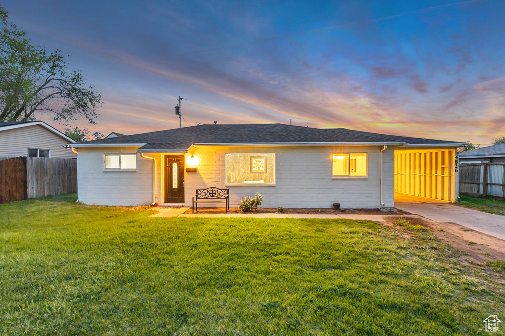 Single story home featuring a lawn, roof with shingles, fence, and brick siding