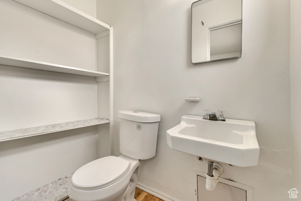 Half bath with wood finished floors, toilet, and a sink