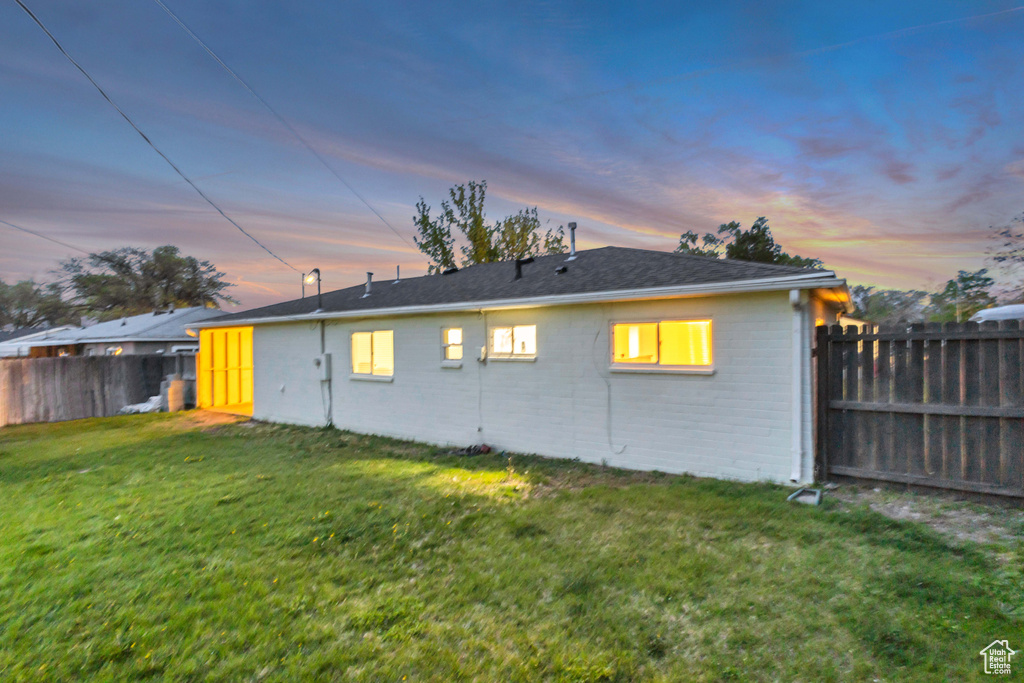 Back of property with brick siding, a fenced backyard, and a yard