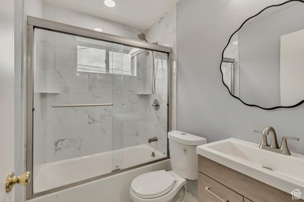 Bathroom featuring bath / shower combo with glass door, vanity, and toilet