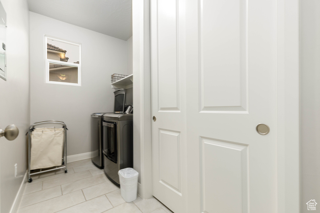 Laundry area featuring washing machine and clothes dryer, light tile patterned floors, and baseboards