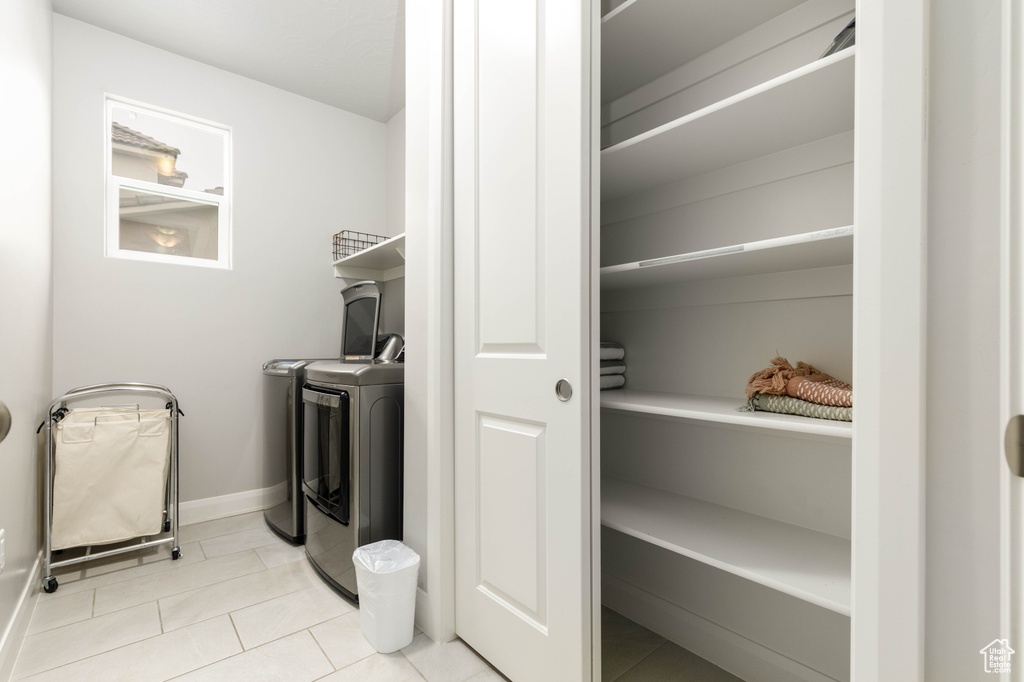 Laundry area with washing machine and dryer, baseboards, and tile patterned flooring