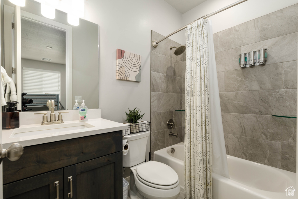 Bathroom with shower / bath combination with curtain, toilet, and vanity
