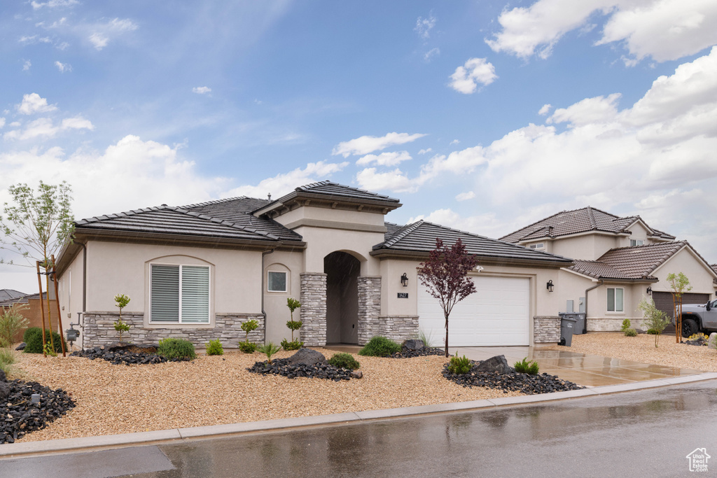 View of front of house with stone siding, stucco siding, and a garage
