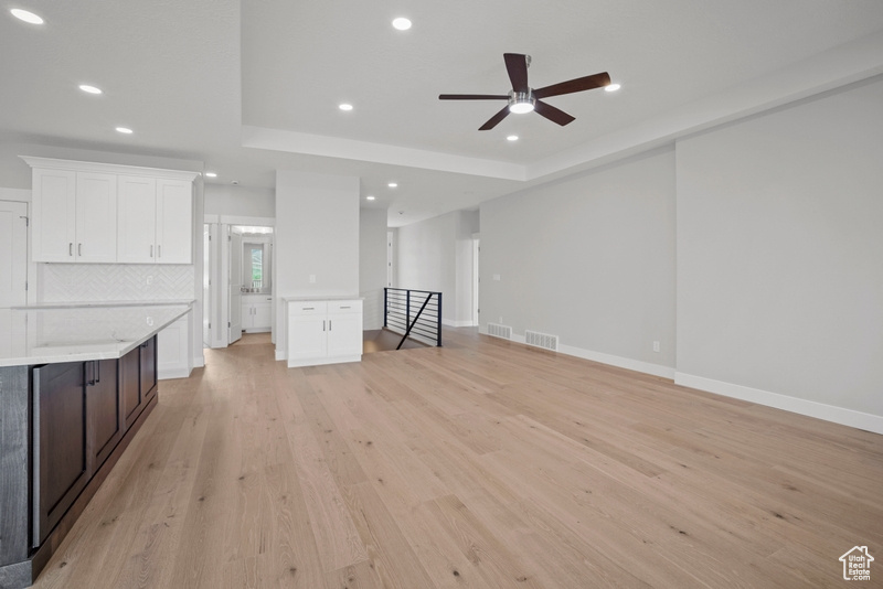 Unfurnished living room with recessed lighting, a ceiling fan, visible vents, and a tray ceiling