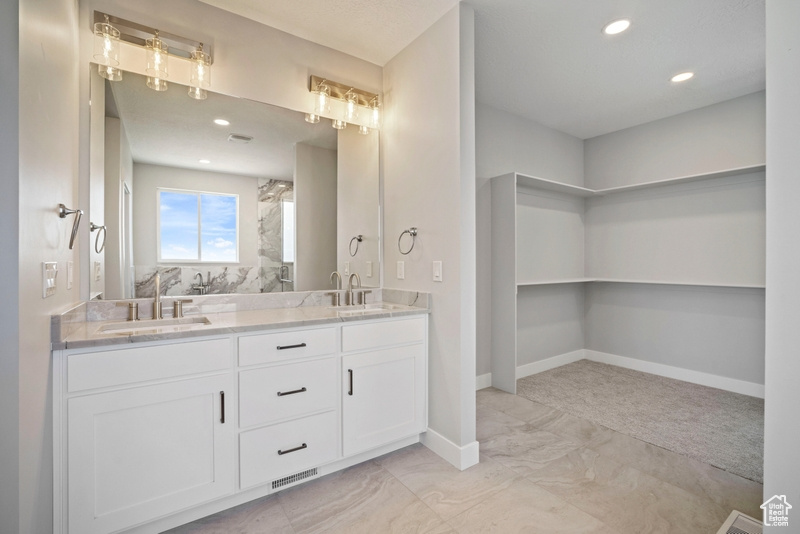 Full bathroom with double vanity, baseboards, marble finish floor, and a sink