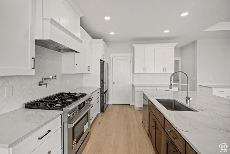 Kitchen featuring appliances with stainless steel finishes, tasteful backsplash, white cabinets, and a sink