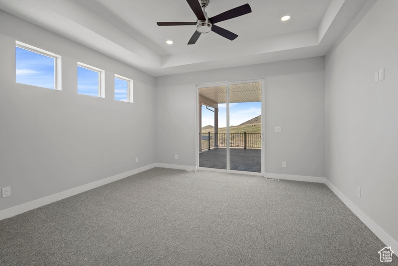 Carpeted empty room with recessed lighting, ceiling fan, a raised ceiling, and a healthy amount of sunlight