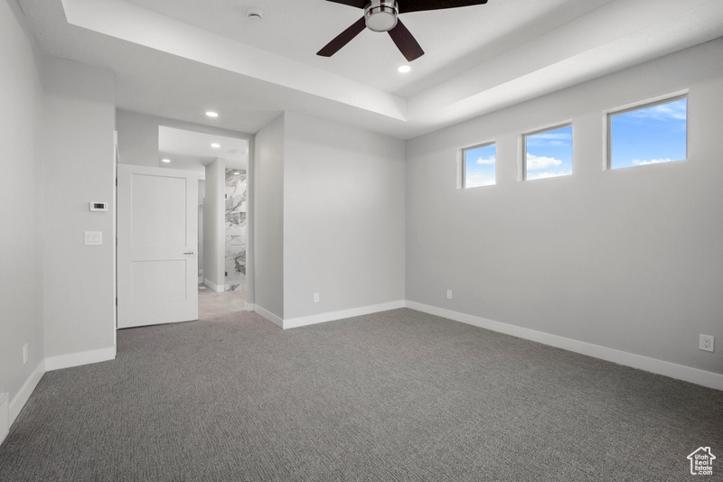 Unfurnished bedroom featuring recessed lighting, a tray ceiling, baseboards, and carpet flooring