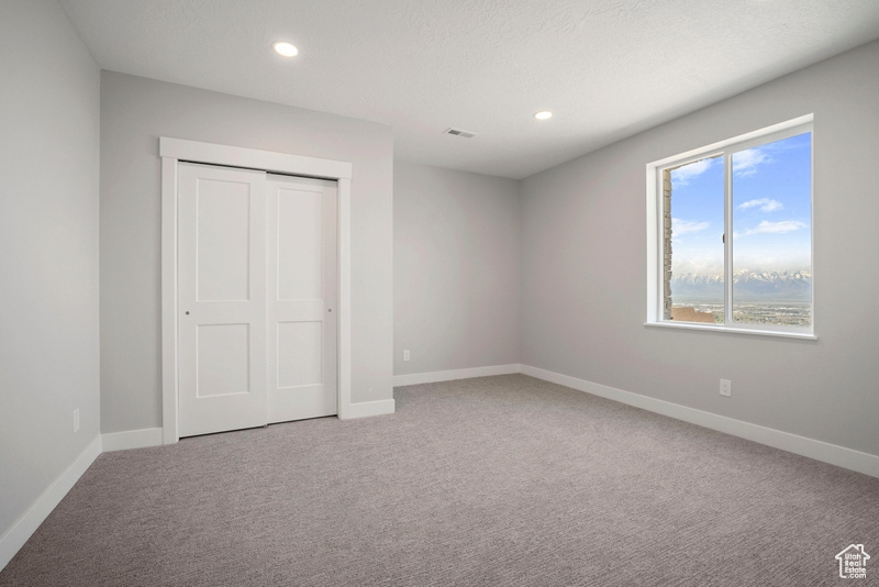 Unfurnished bedroom featuring visible vents, a closet, baseboards, recessed lighting, and carpet