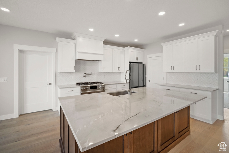 Kitchen featuring stainless steel appliances, backsplash, light wood finished floors, and a sink