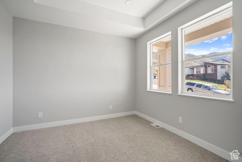 Carpeted empty room with baseboards and visible vents
