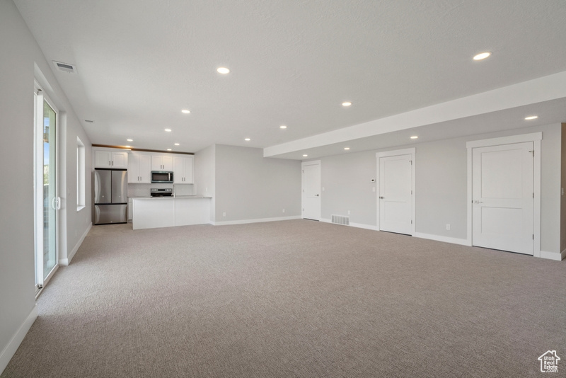 Unfurnished living room with recessed lighting, light carpet, and baseboards