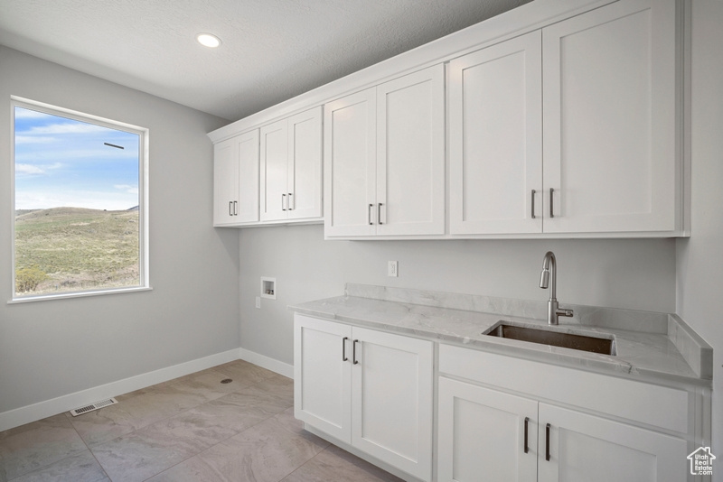 Washroom featuring a sink, baseboards, hookup for a washing machine, recessed lighting, and cabinet space