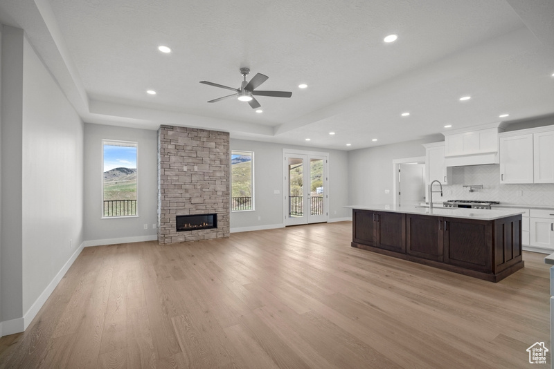 Kitchen featuring a kitchen island with sink, a ceiling fan, a healthy amount of sunlight, and light countertops