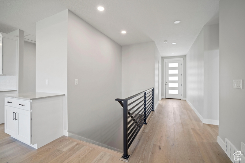 Hallway with recessed lighting, an upstairs landing, visible vents, and light wood-type flooring