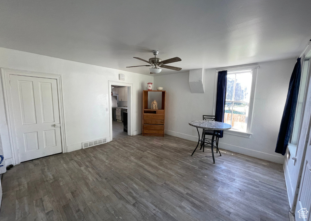 Interior space with a ceiling fan, visible vents, wood finished floors, and baseboards