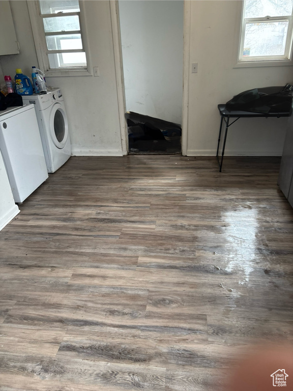 Clothes washing area featuring dark wood finished floors, baseboards, and washer and clothes dryer