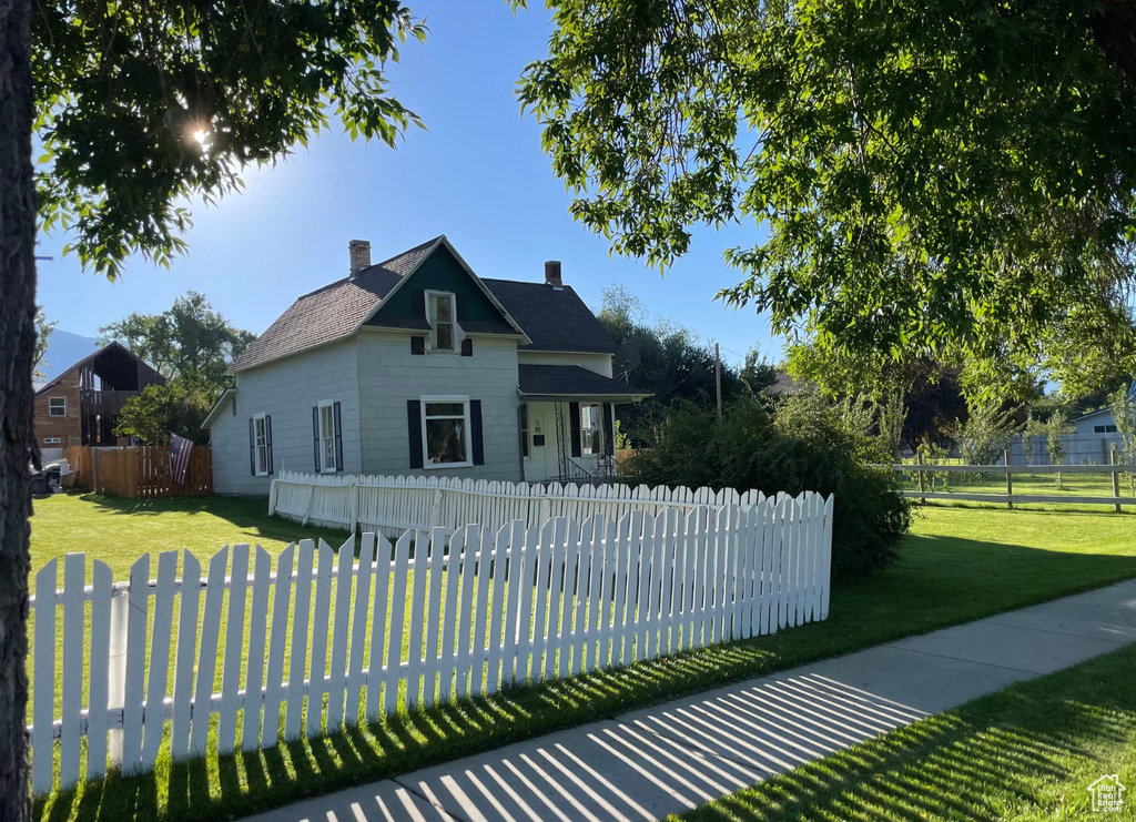 View of front facade with a chimney, a front lawn, and a fenced front yard