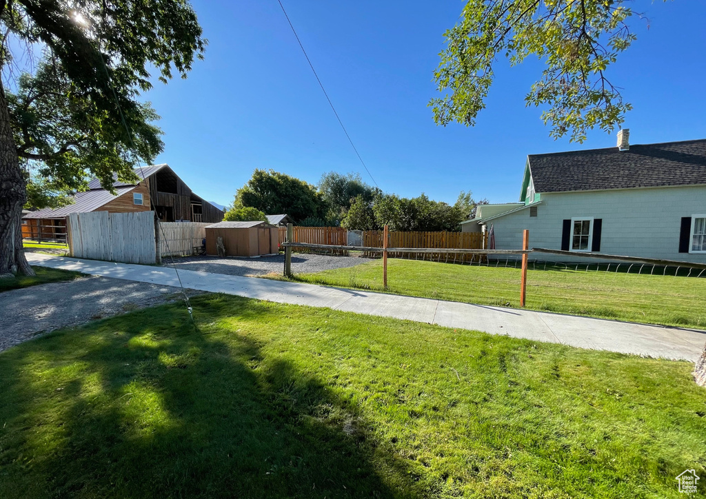 View of yard with fence, a shed, and an outbuilding