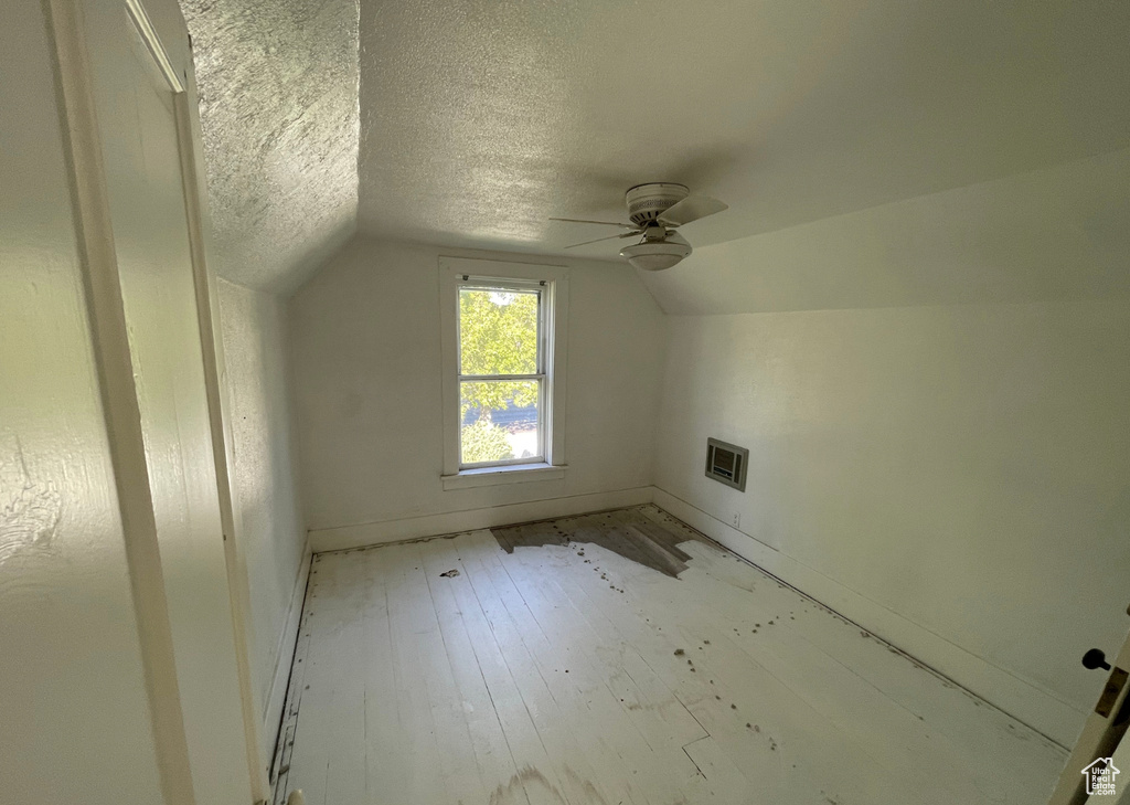 Bonus room with vaulted ceiling, baseboards, visible vents, a ceiling fan, and a textured ceiling