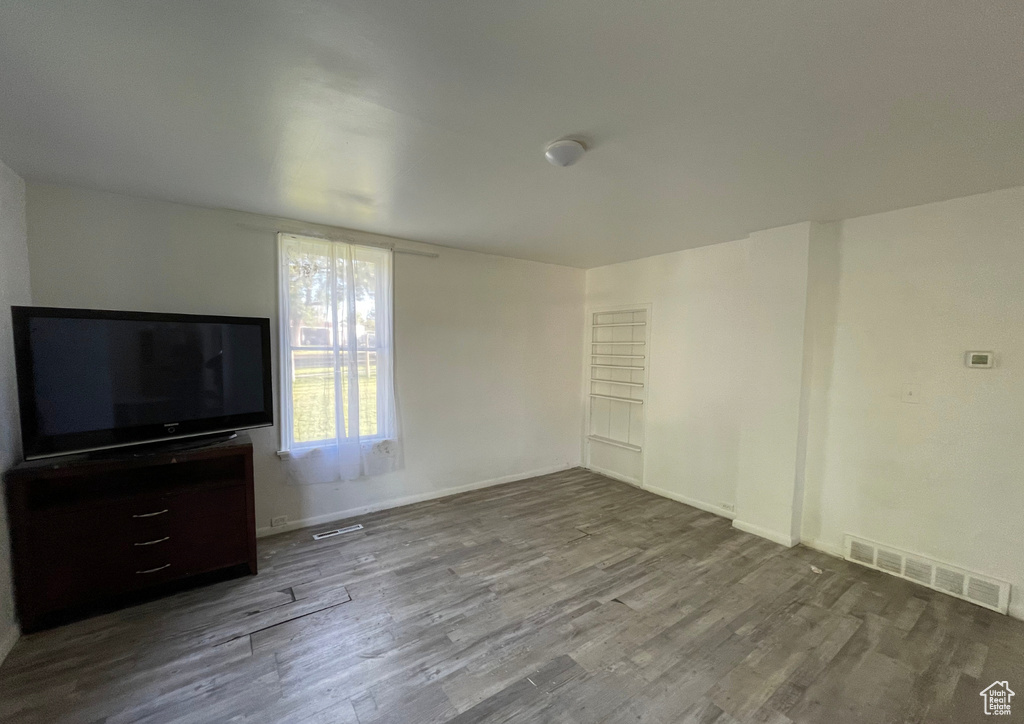 Unfurnished living room featuring baseboards, visible vents, and wood finished floors