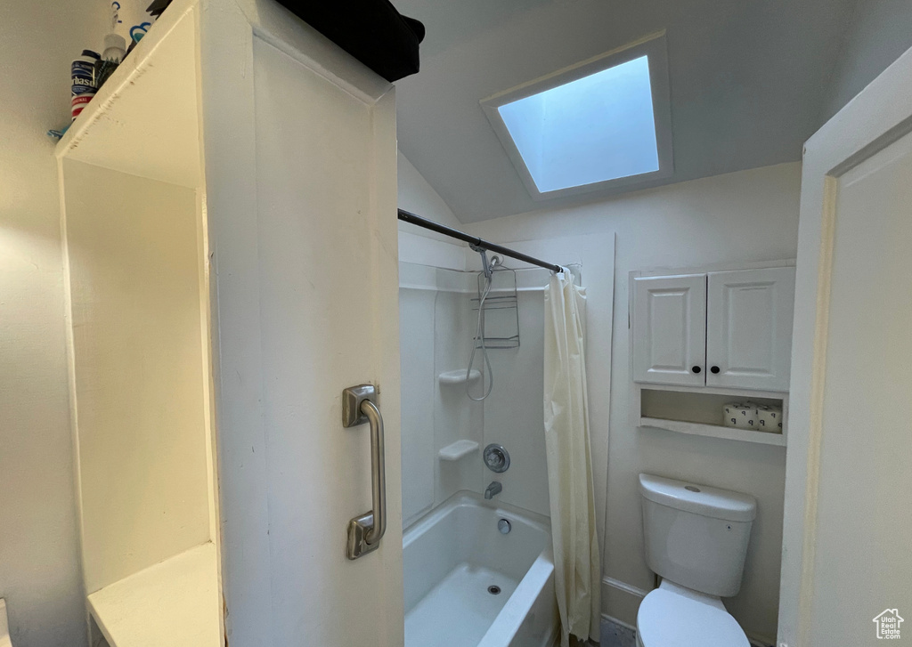 Full bath featuring shower / bathtub combination with curtain, toilet, and vaulted ceiling with skylight