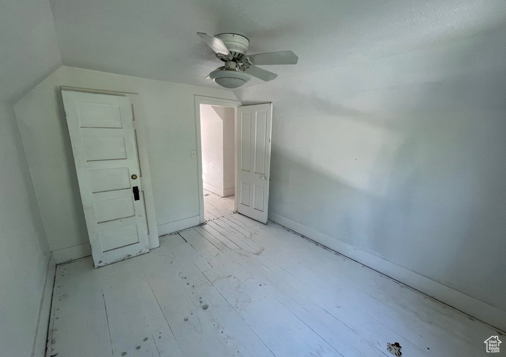 Unfurnished bedroom with a ceiling fan, light wood-style flooring, lofted ceiling, and baseboards