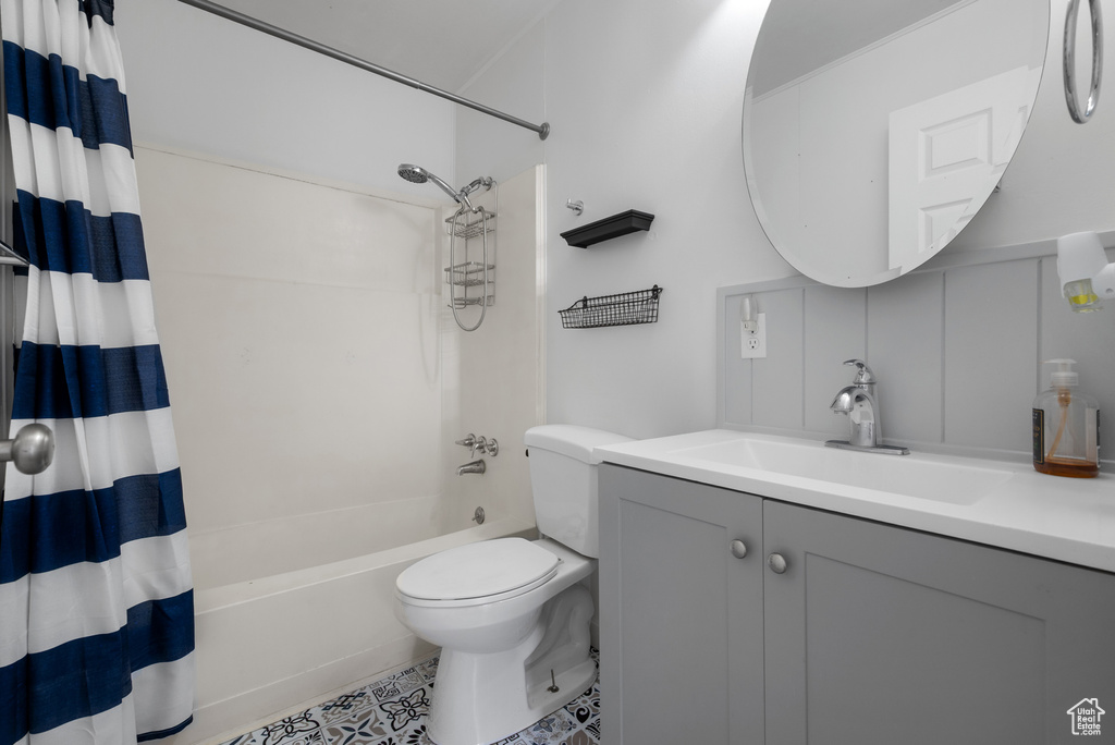 Full bathroom with shower / bath combo with shower curtain, toilet, vanity, and tile patterned floors