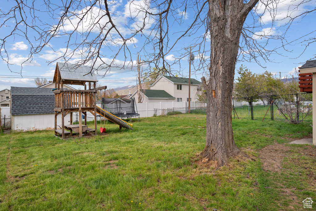 View of yard featuring a trampoline, a playground, and a residential view