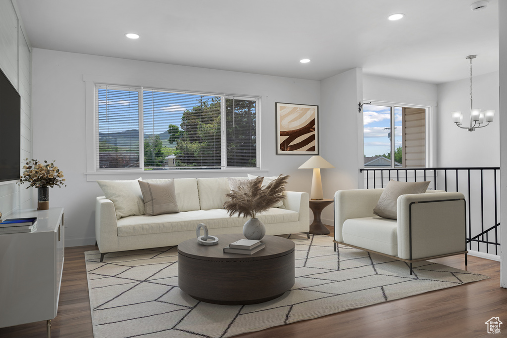 Living room featuring healthy amount of natural light, wood finished floors, a chandelier, recessed lighting, and baseboards
