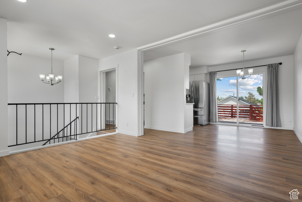Unfurnished room with a chandelier, baseboards, wood finished floors, and recessed lighting