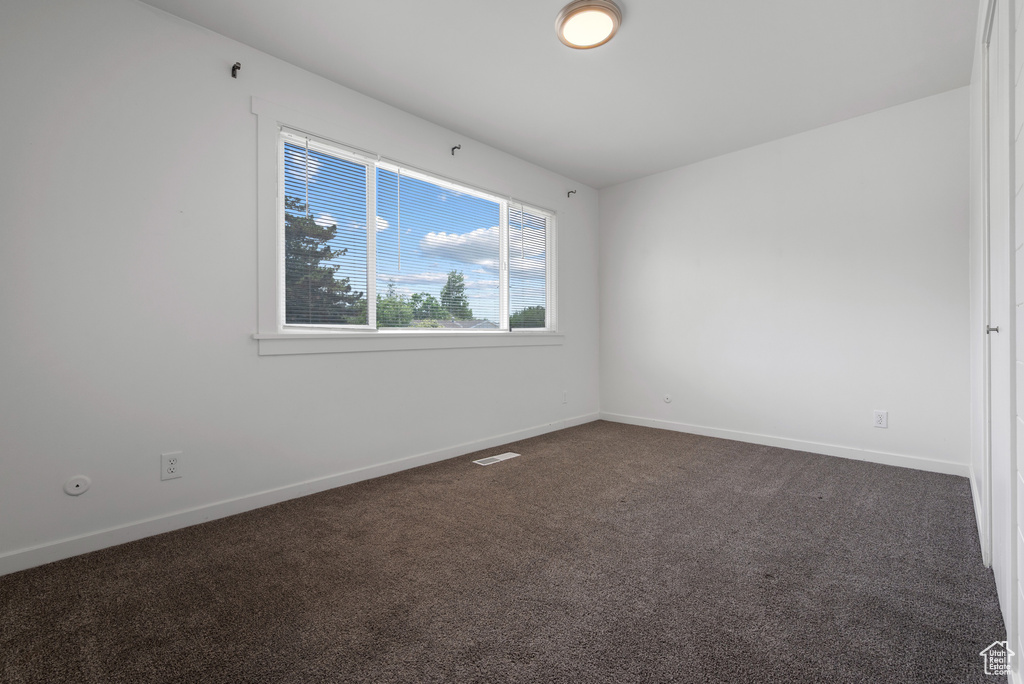 Empty room with dark colored carpet and baseboards