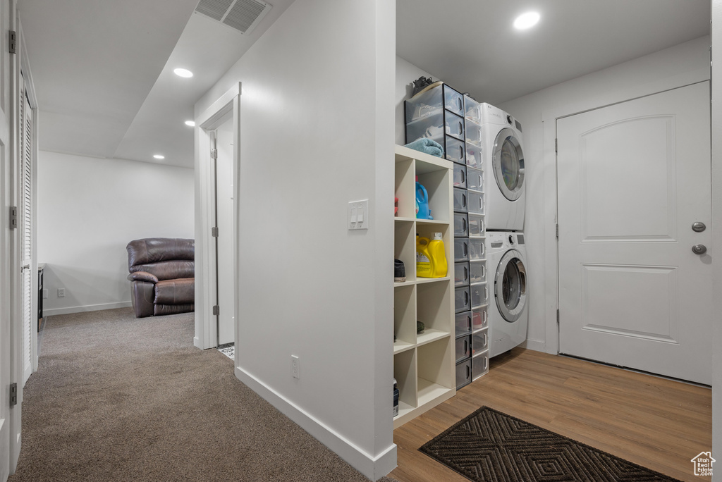 Laundry room featuring stacked washer / drying machine, recessed lighting, baseboards, and wood finished floors