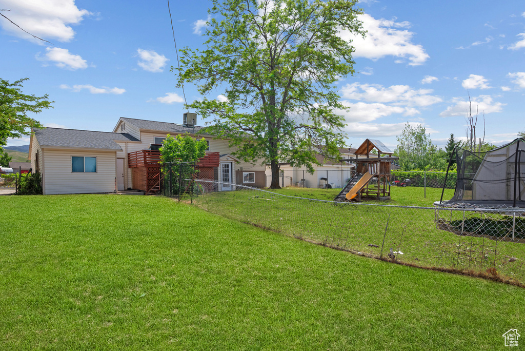 View of yard featuring a trampoline and a playground
