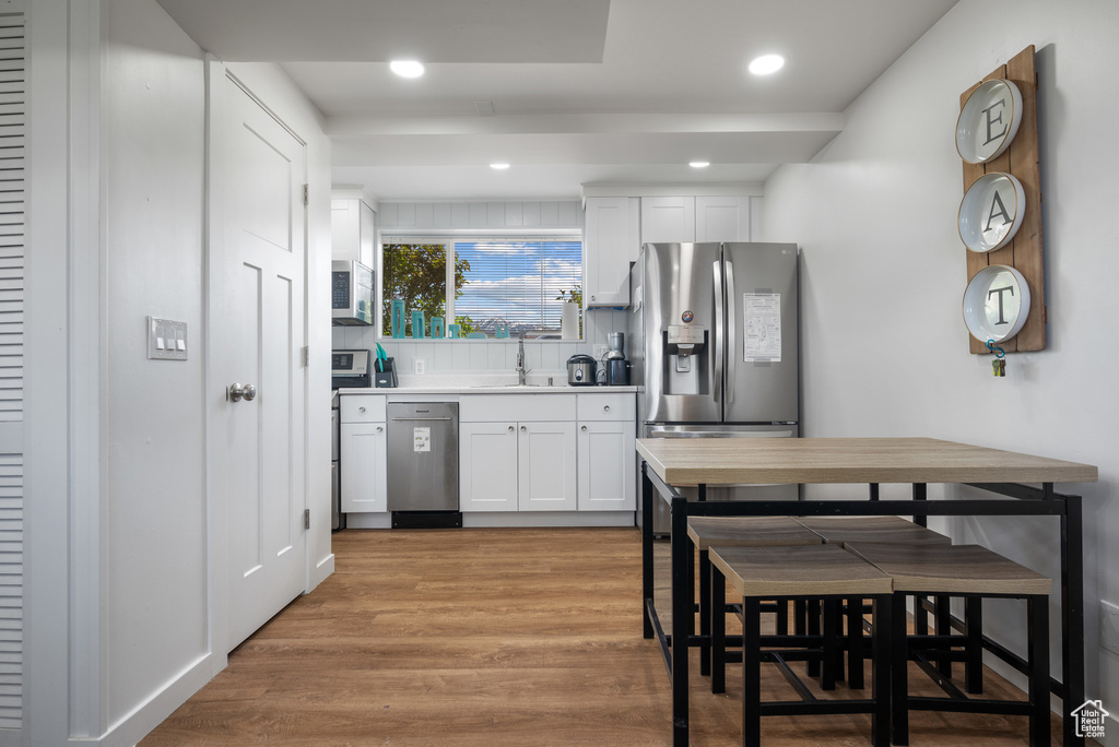 Kitchen featuring appliances with stainless steel finishes, a sink, light wood-style floors, white cabinets, and recessed lighting
