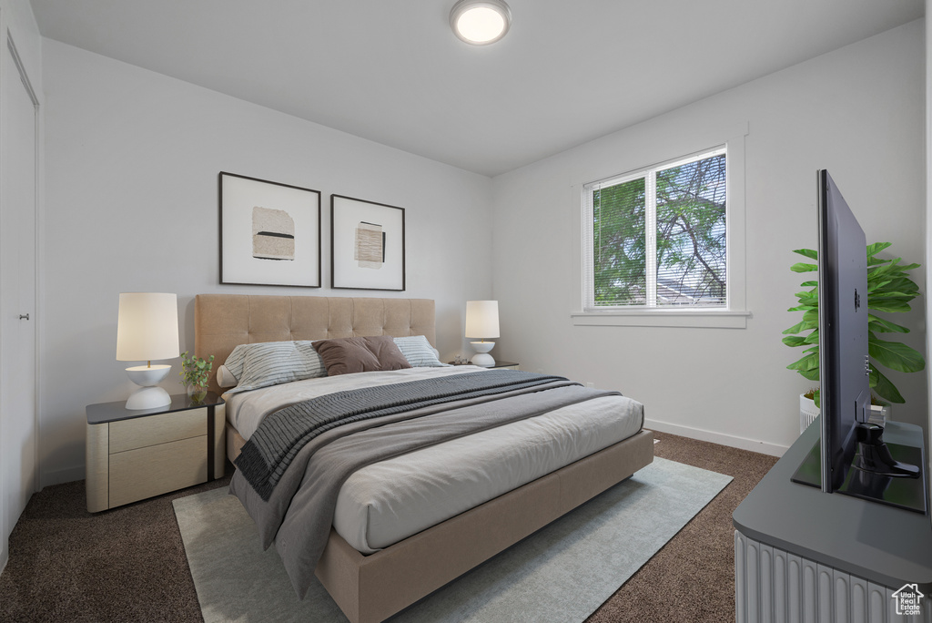 Bedroom with dark carpet and baseboards