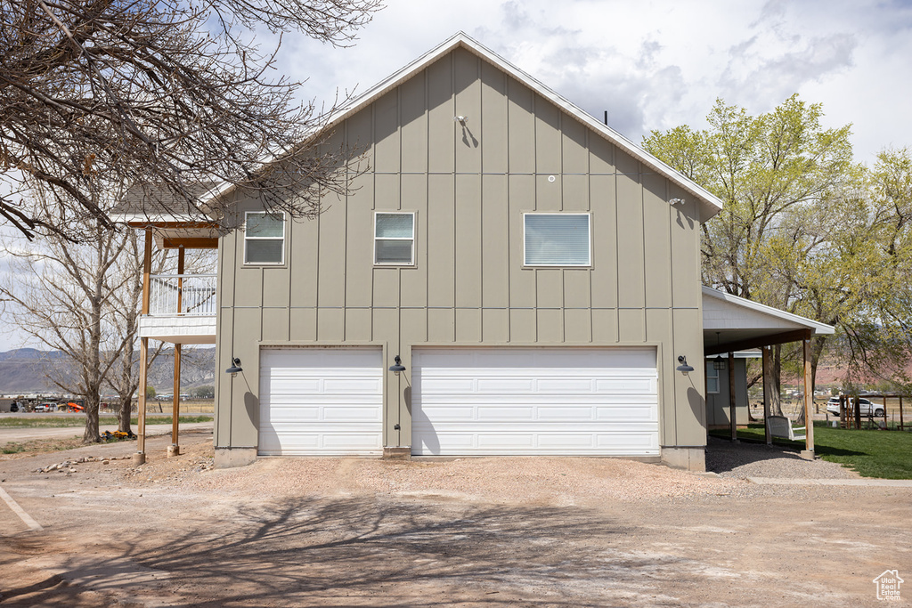 View of side of property featuring board and batten siding, dirt driveway, and an attached garage