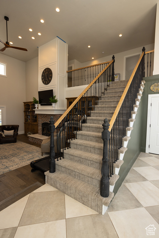Stairs with recessed lighting, a ceiling fan, and a fireplace