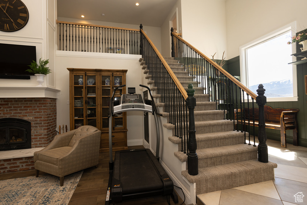 Staircase with recessed lighting, a high ceiling, and a fireplace