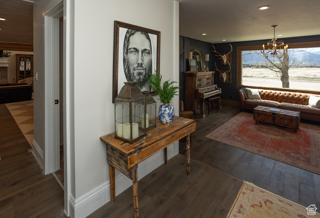 Living area with dark wood-style floors, recessed lighting, a notable chandelier, and baseboards