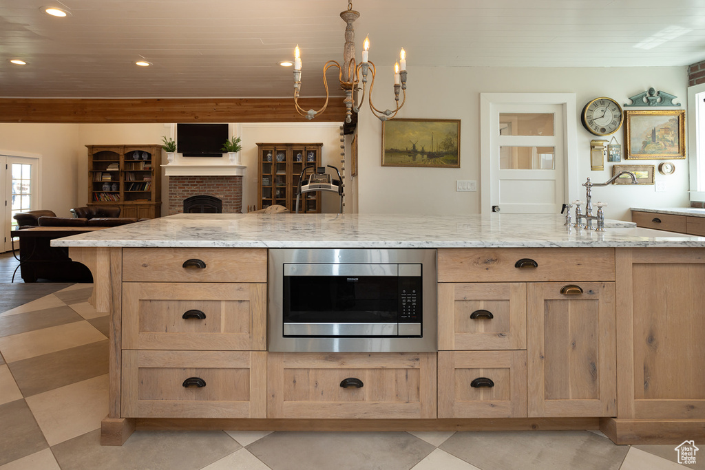 Kitchen featuring light stone counters, stainless steel microwave, light brown cabinetry, open floor plan, and recessed lighting