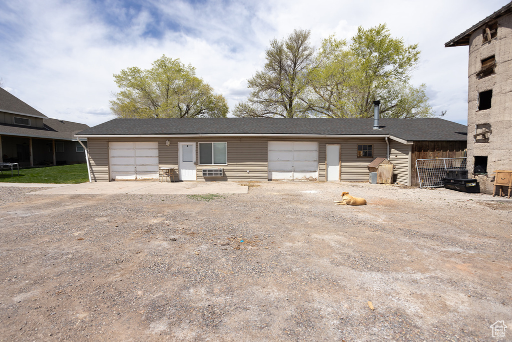 View of front of property with dirt driveway and an attached garage