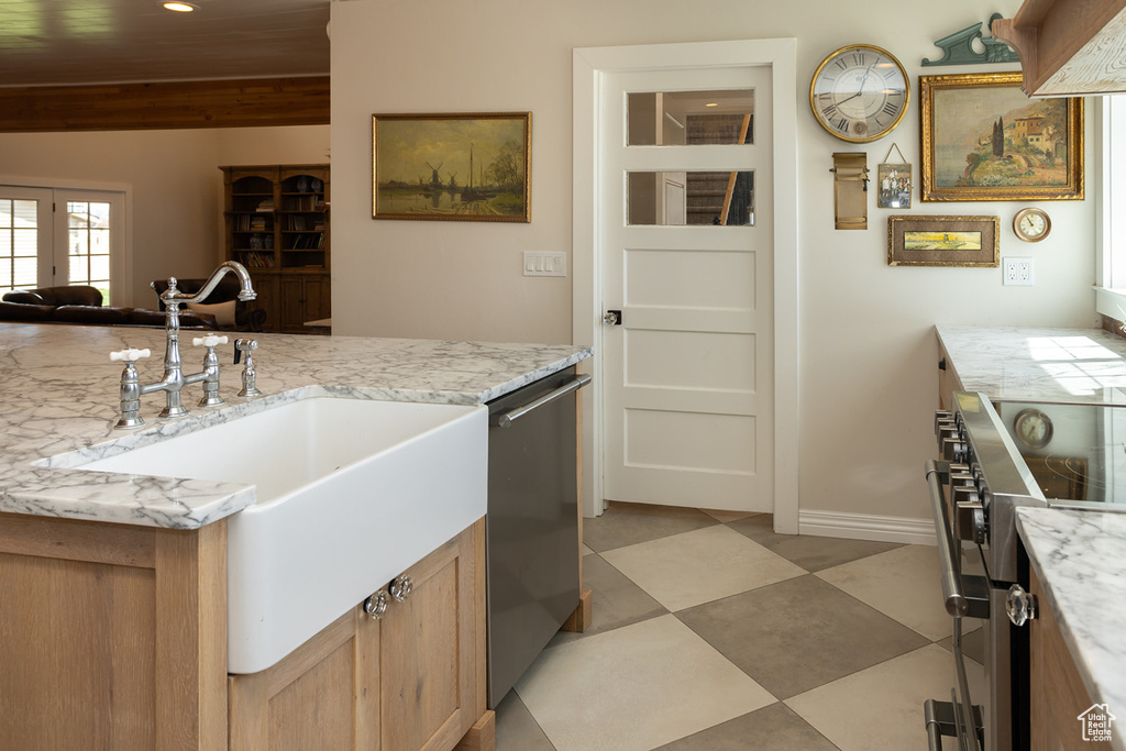 Kitchen featuring light stone counters, stainless steel appliances, baseboards, and a sink