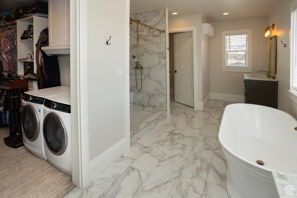 Bathroom featuring a soaking tub, separate washer and dryer, marble finish floor, and tiled shower