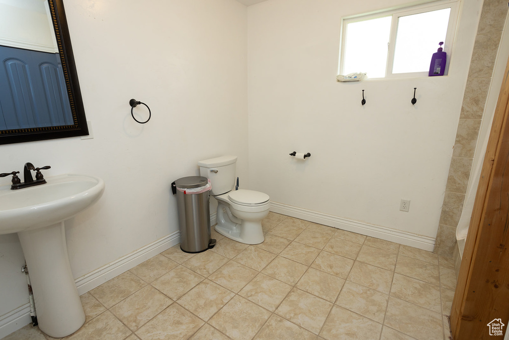 Bathroom with baseboards, tile patterned floors, toilet, and a sink