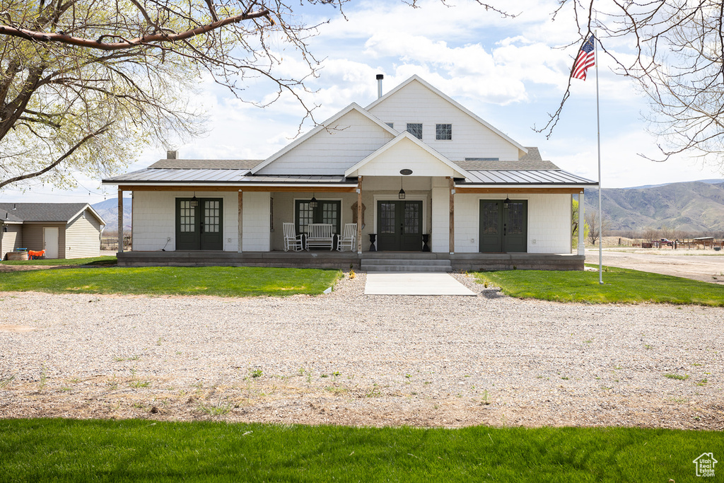 View of front of property featuring a porch, a standing seam roof, metal roof, french doors, and a front yard