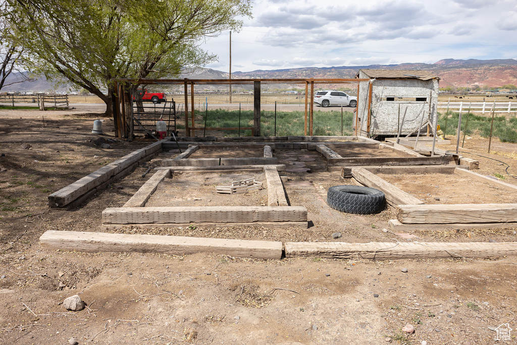 View of yard featuring a mountain view, a vegetable garden, and fence